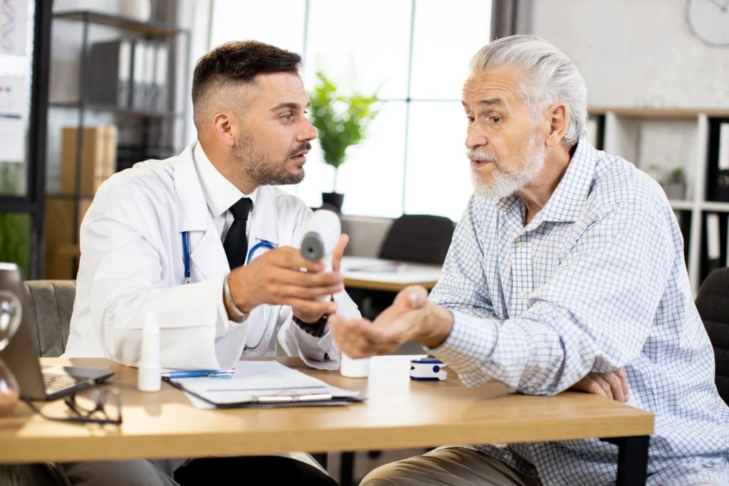 Doctor showing infrared thermometer for his aged patient. Healthcare devices