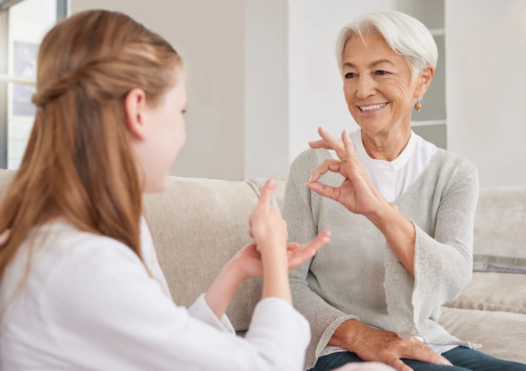 Senior woman, sign language and deaf girl communication, talking or conversation in home. Support, .