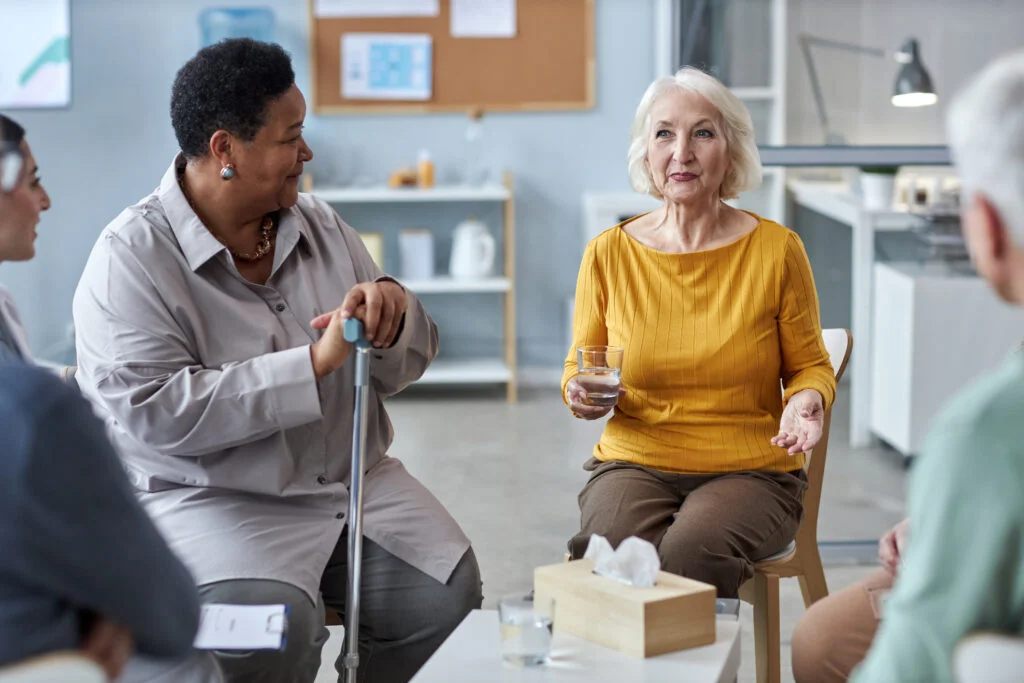 Two senior women sharing stories at mental health support group